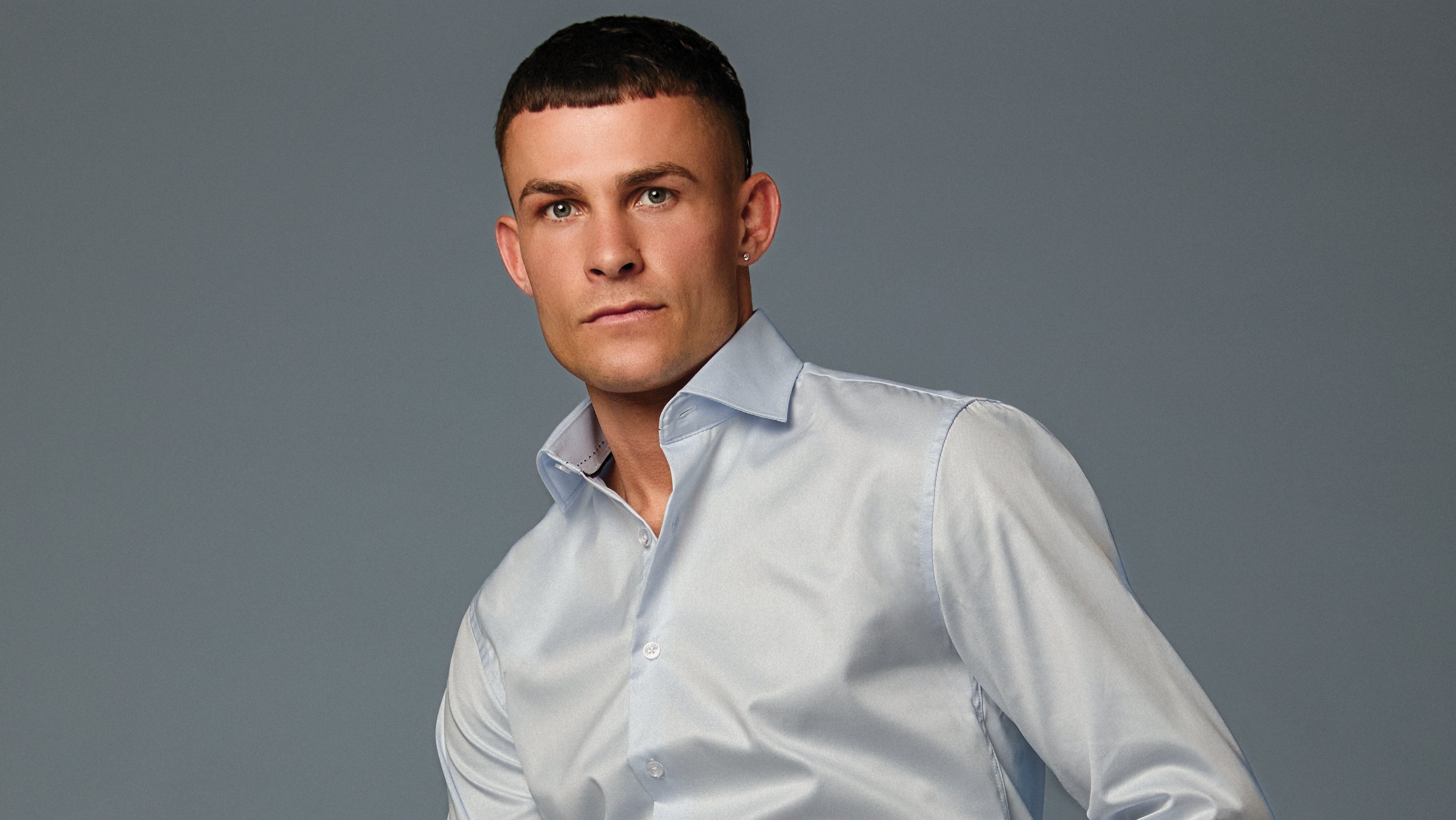 Man wearing a light blue shirt against a gray background