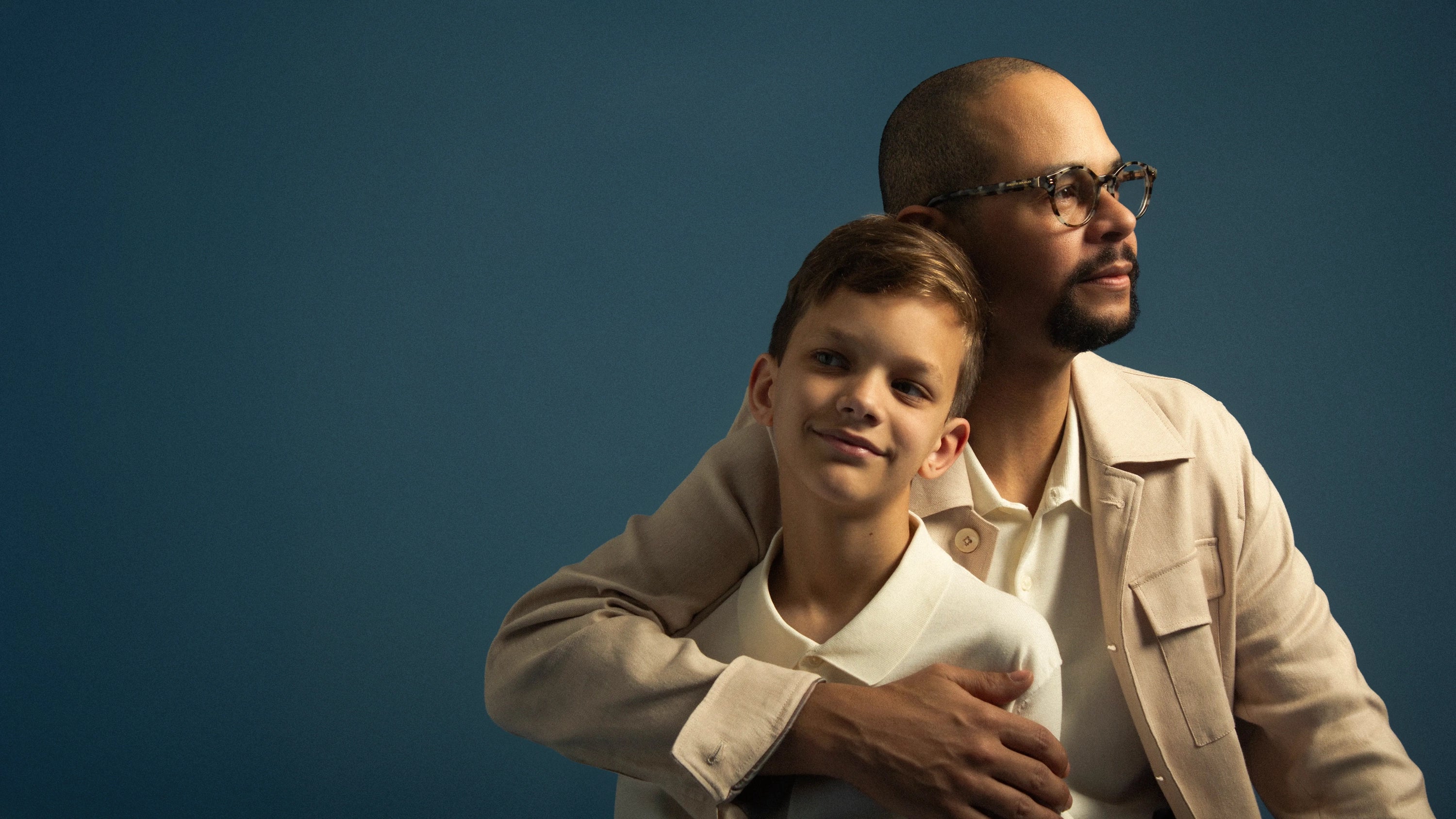Father and son hugging against a blue background