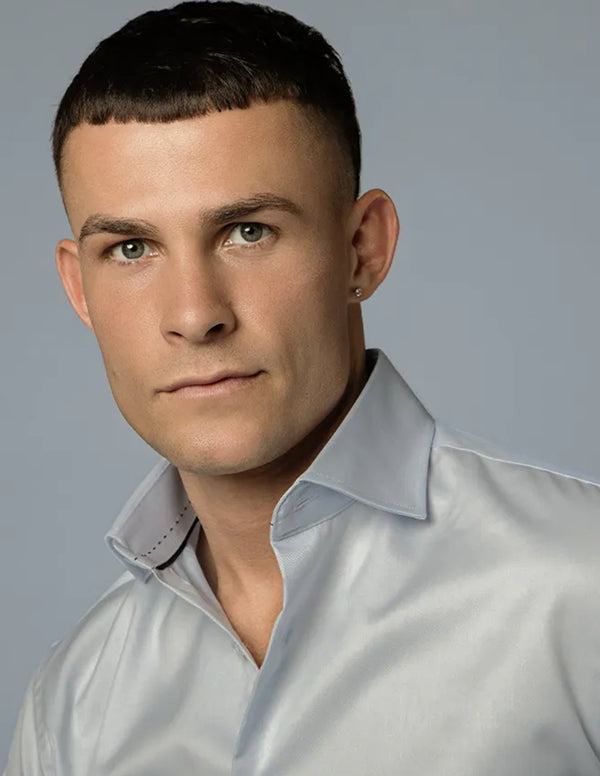Man wearing a light blue shirt against a plain background