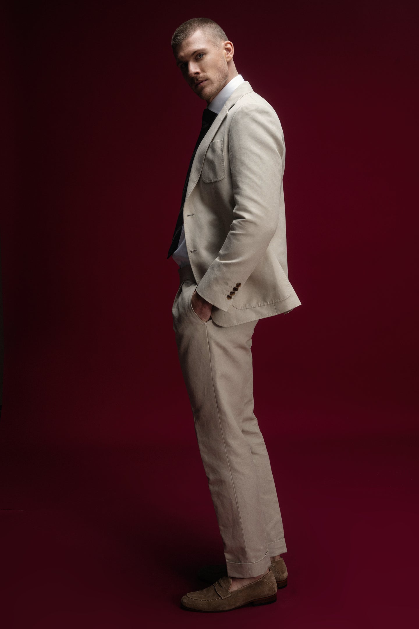 Man in a beige suit standing against a red background
