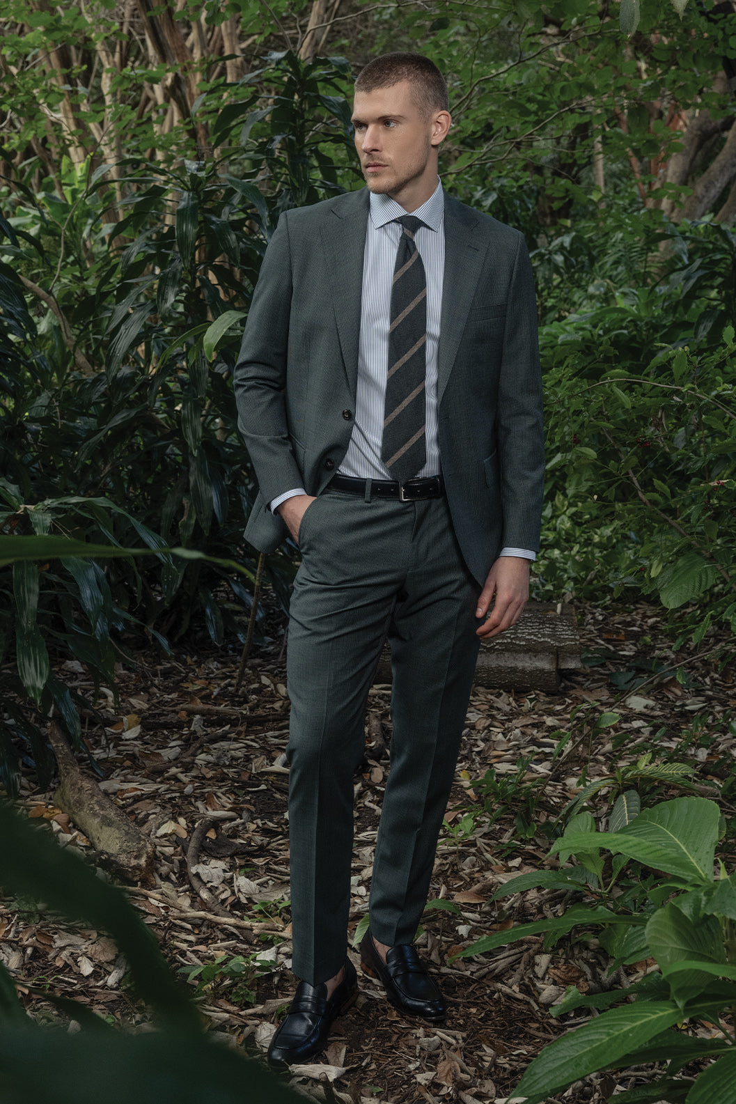 Man in a suit standing in a forest setting