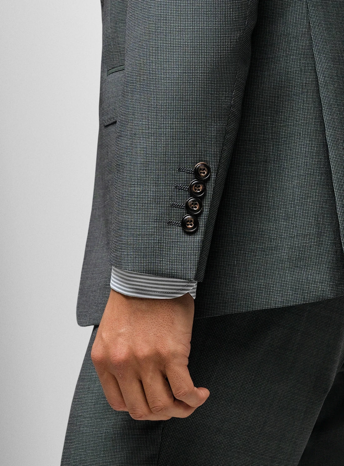 Gray checkered suit jacket with a hand visible, on a light gray background