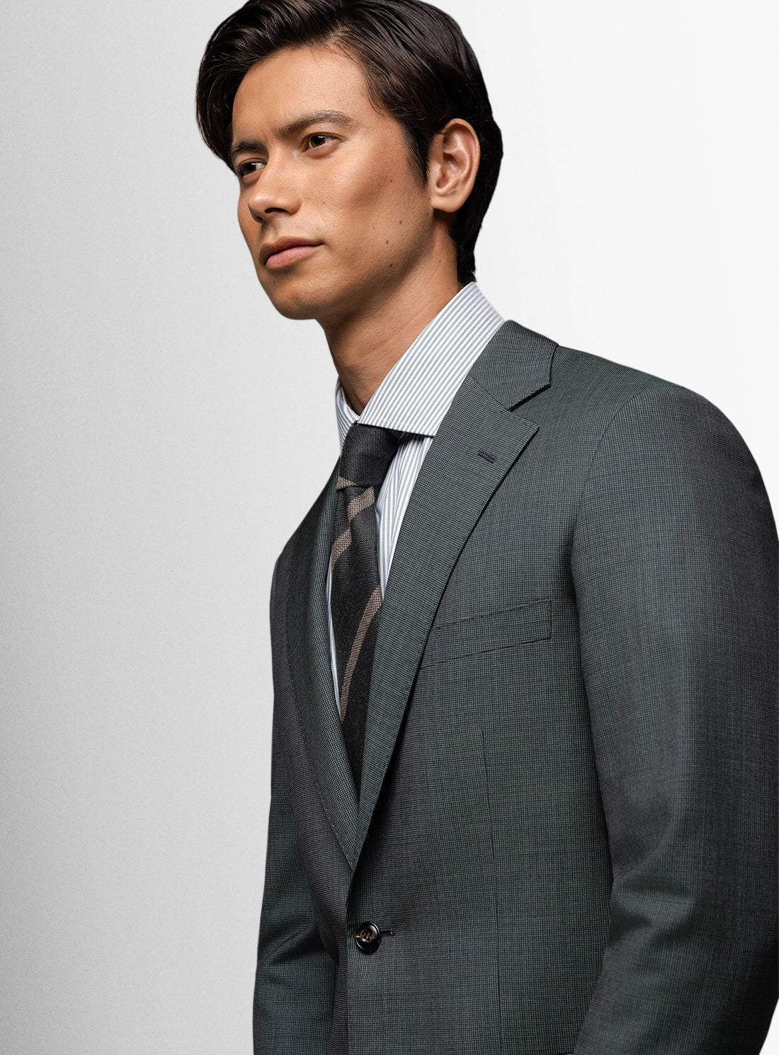 Man wearing a gray suit and tie against a light gray background