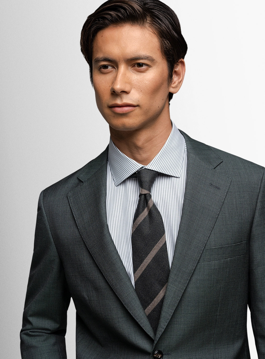 Man wearing a gray suit with a striped tie against a light gray background