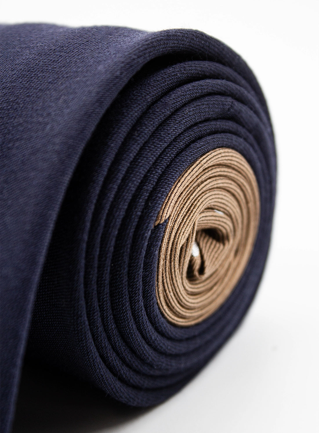 Rolled-up navy blue fabric with a beige center on a white background