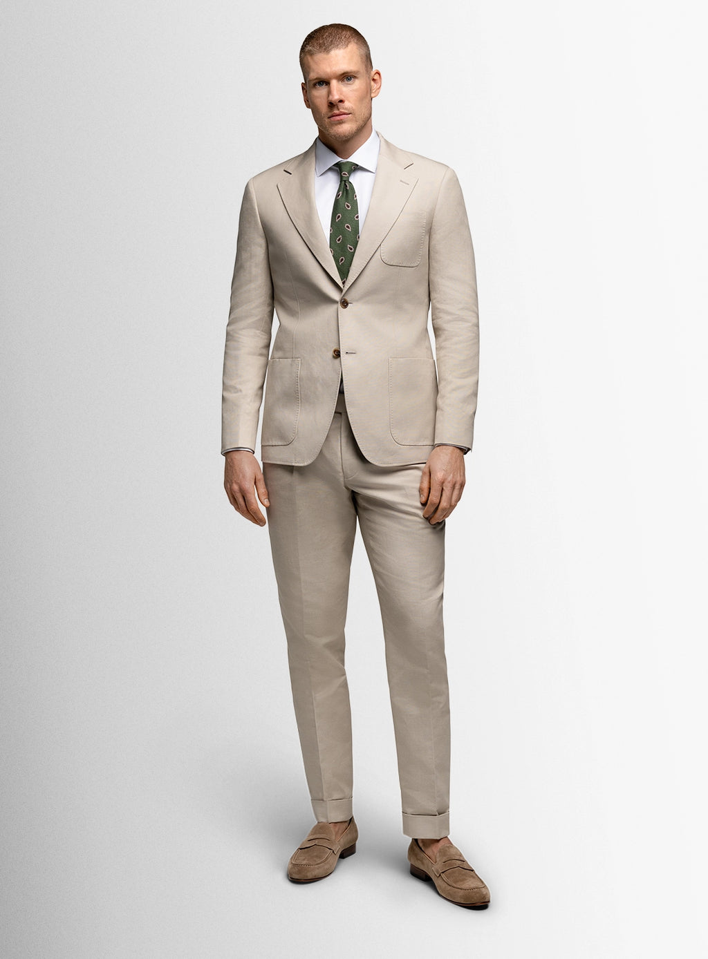 Man wearing a beige suit with a green tie on a white background