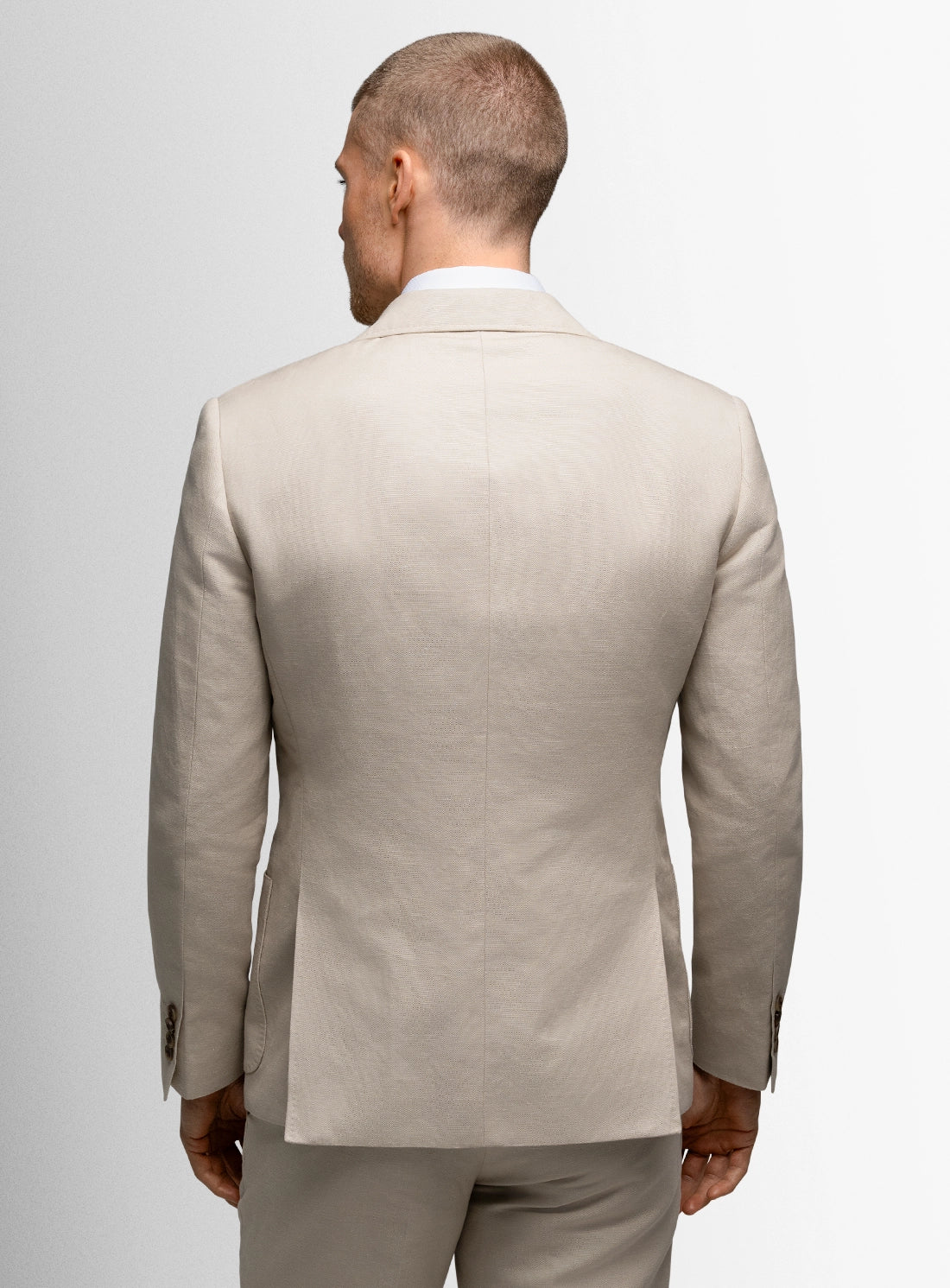 Man wearing a beige suit against a plain background