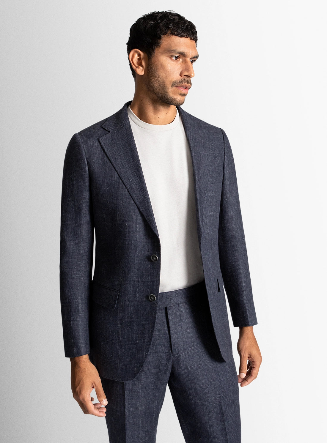 Man wearing a navy suit with a white shirt on a light gray background