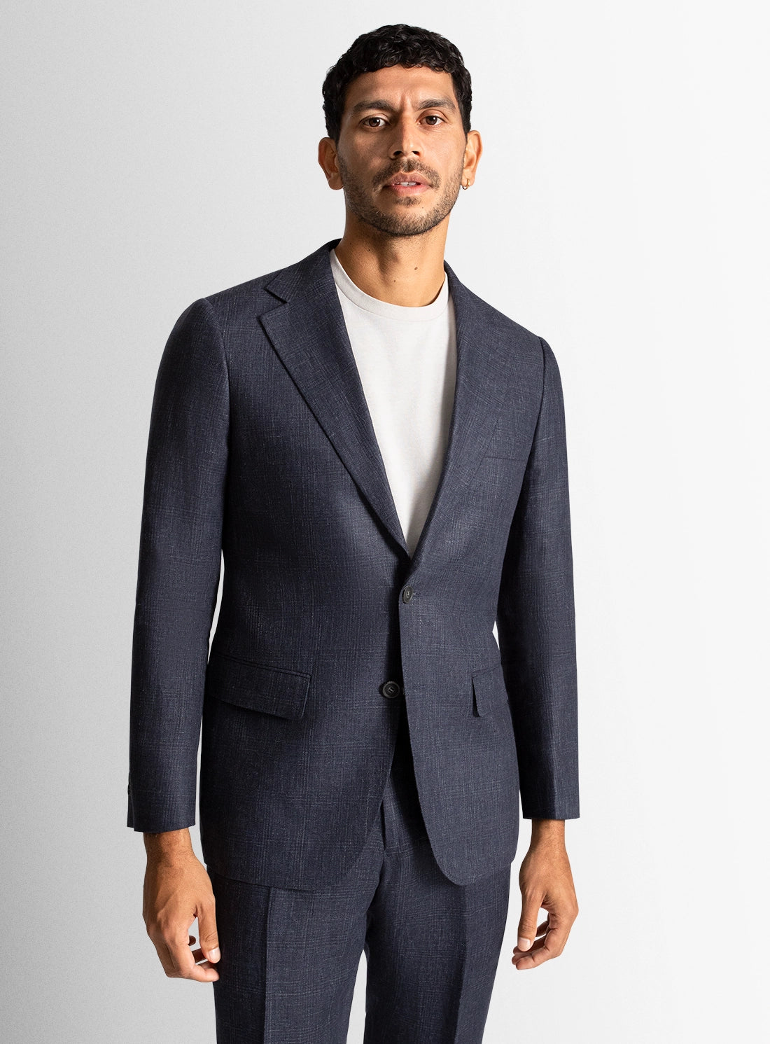 Man wearing a navy suit with a white shirt on a light gray background