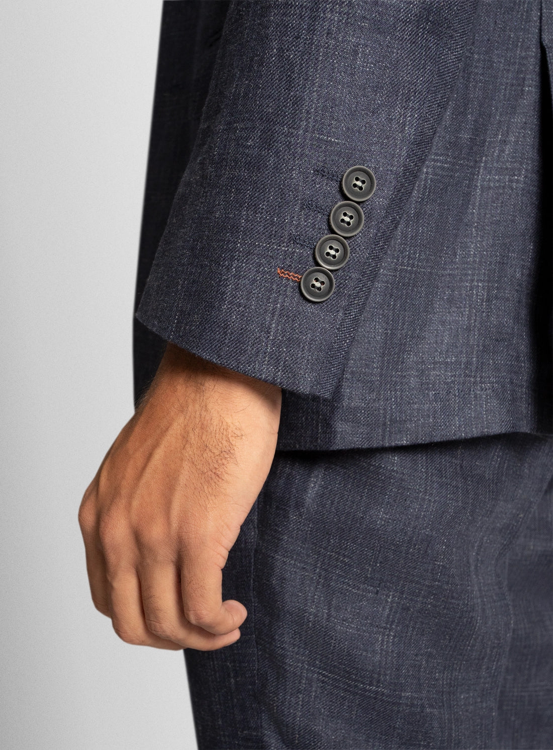 Close-up of a dark blue suit with three buttons on a light gray background