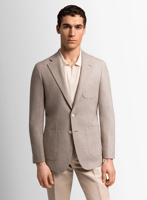 Man wearing a beige suit jacket and pants on a light gray background