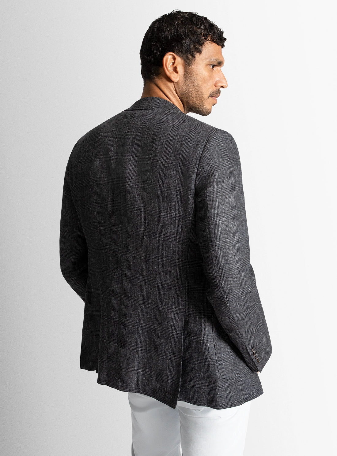 Man wearing a gray blazer and white pants against a light gray background