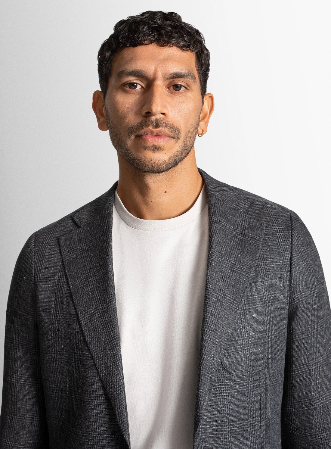 Man wearing a gray blazer over a white shirt against a plain background