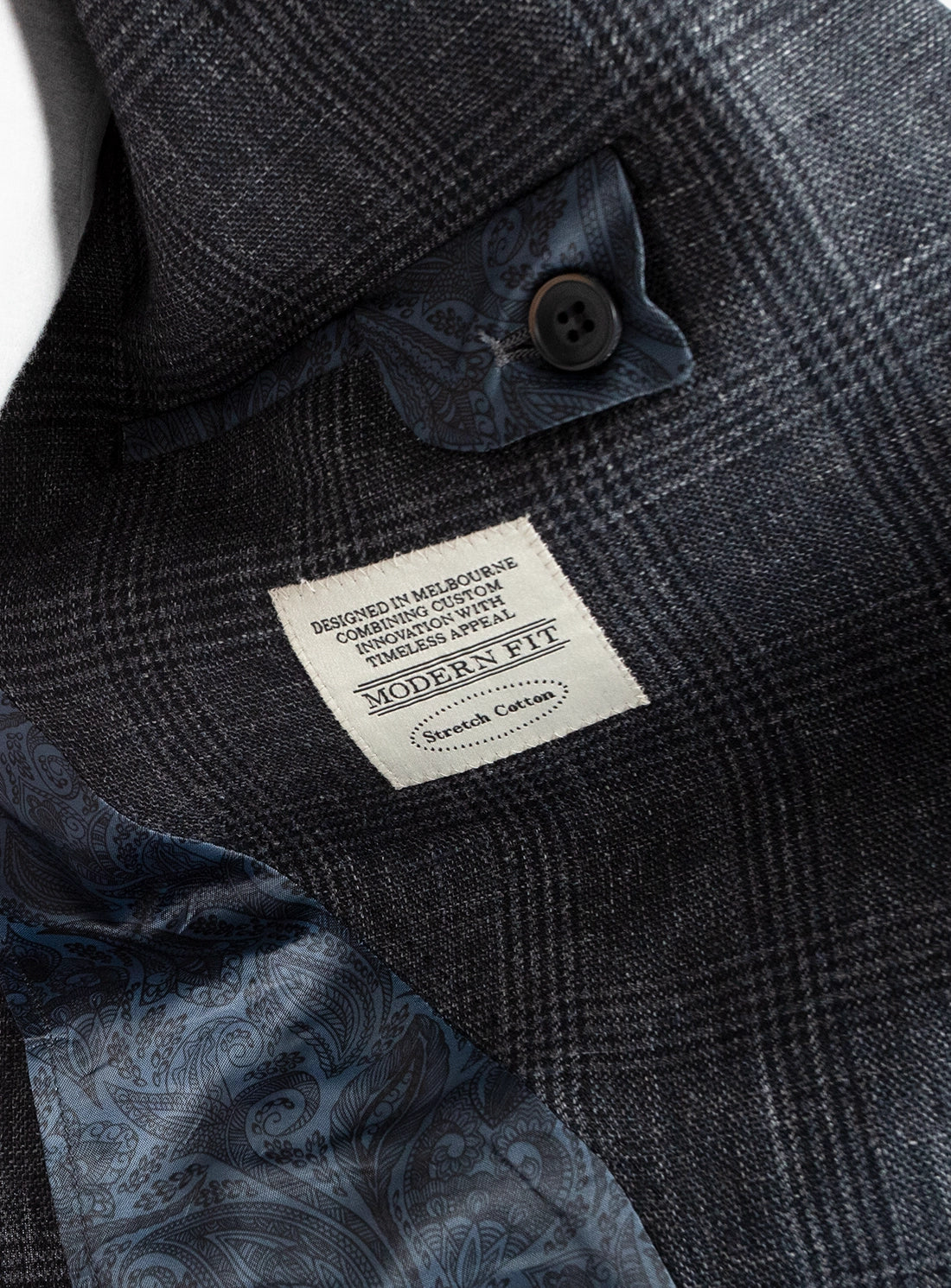 Close-up of a dark gray checkered jacket with a brand label on a blurred background