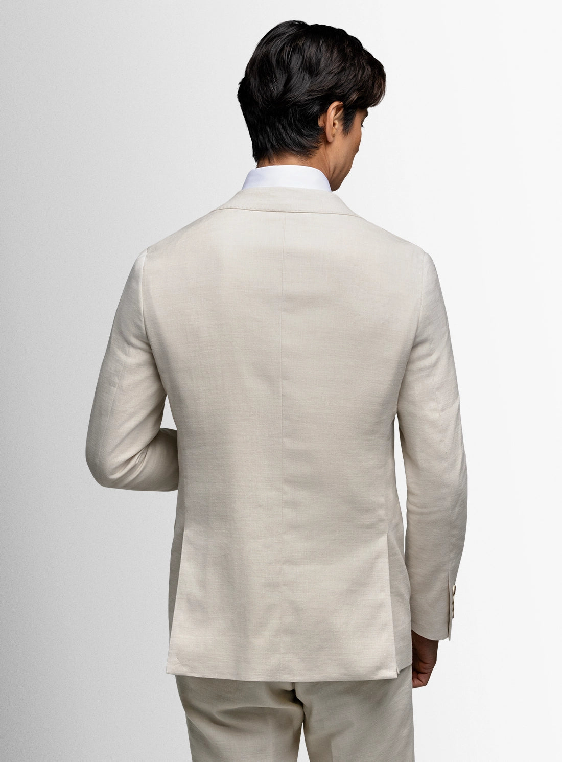 Man wearing a beige suit against a plain background