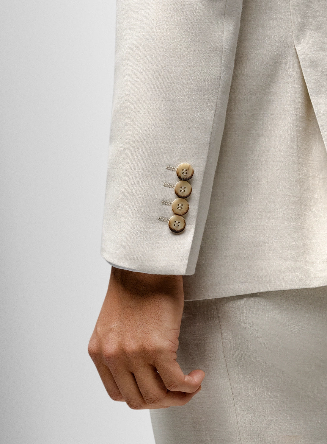 Close-up of a beige suit jacket with buttons on a light gray background