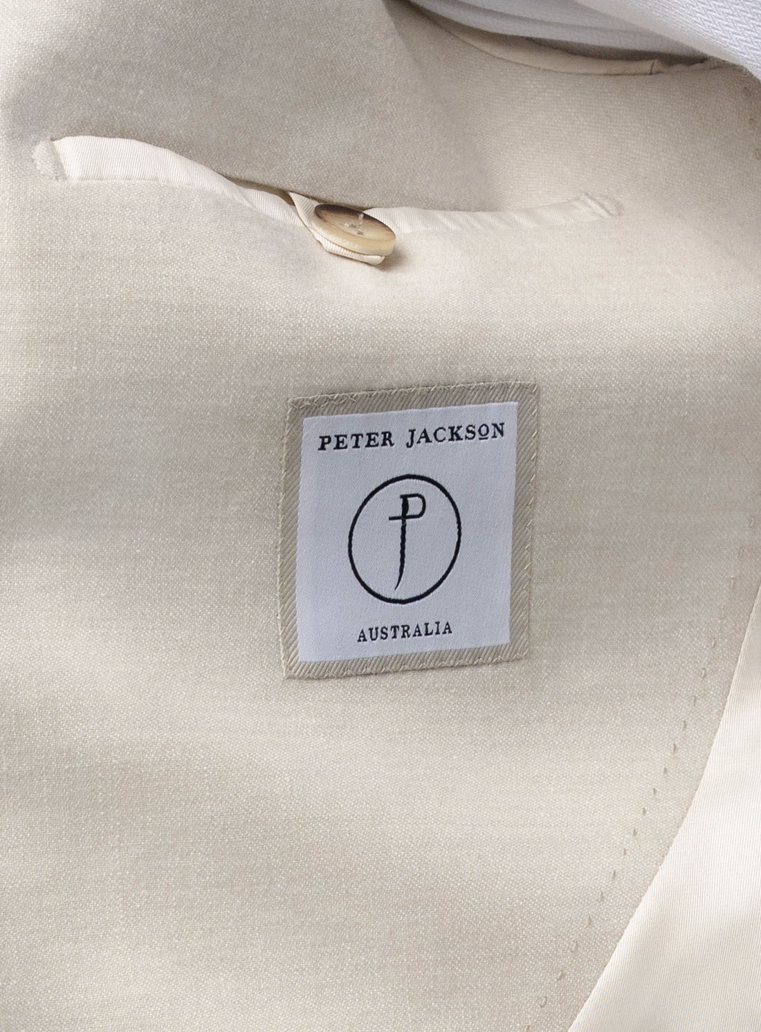 Close-up of a 'Peter Jackson Australia' label on a beige fabric background