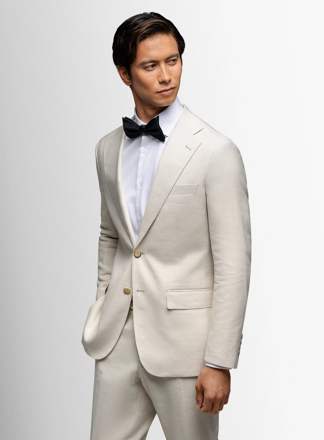 Man wearing a light gray suit with a black bow tie on a white background