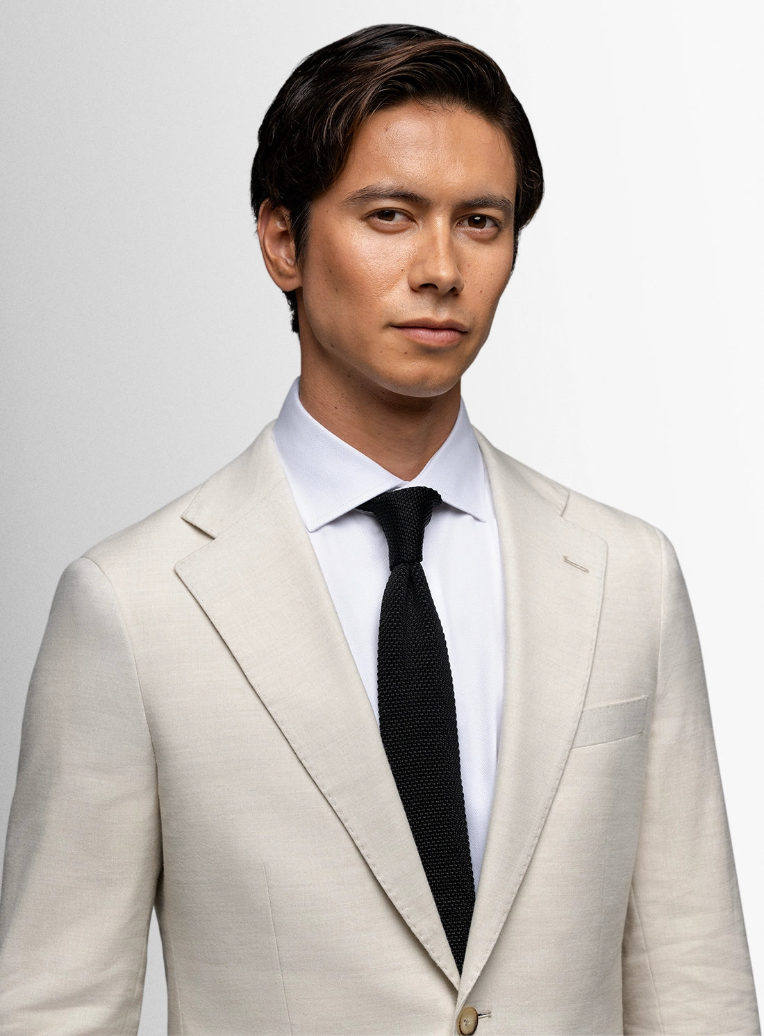 Man wearing a light gray suit with a black tie on a white background
