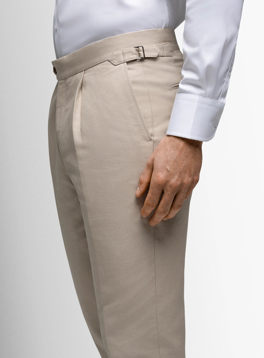 Beige dress pants worn with a white shirt on a light gray background