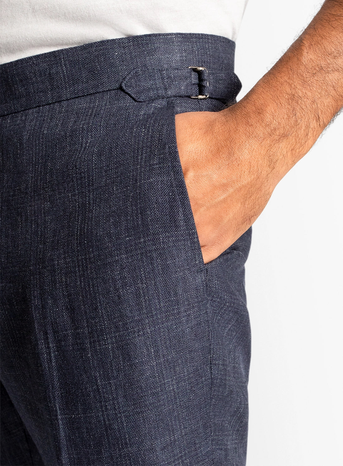 Navy blue pants with a white shirt underneath on a plain background
