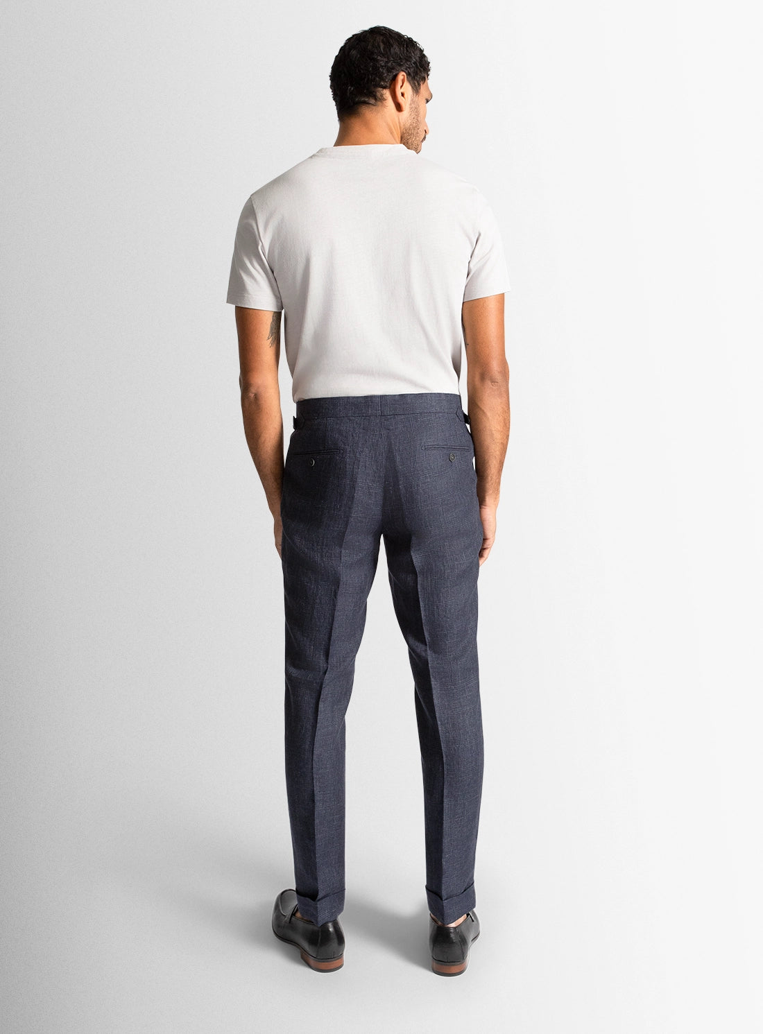 Man wearing a white t-shirt and dark gray pants on a white background