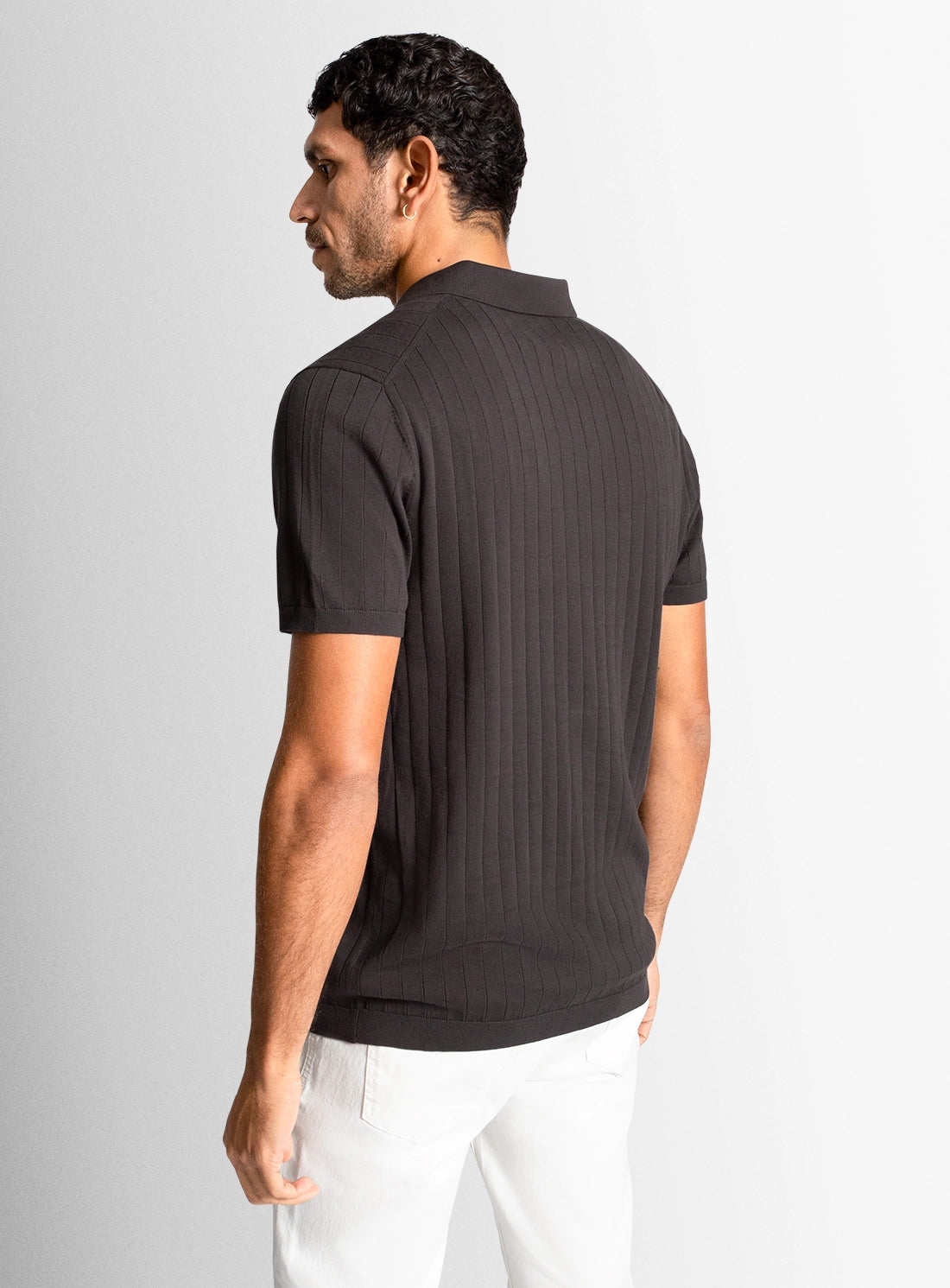 Man wearing a dark gray ribbed polo shirt on a light gray background