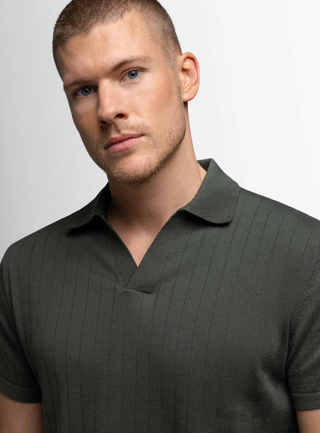 Man wearing a dark green polo shirt against a light gray background