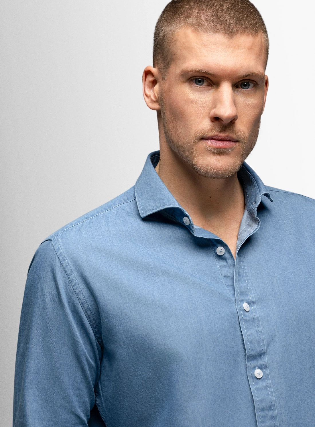 Man wearing a light blue shirt against a gray background