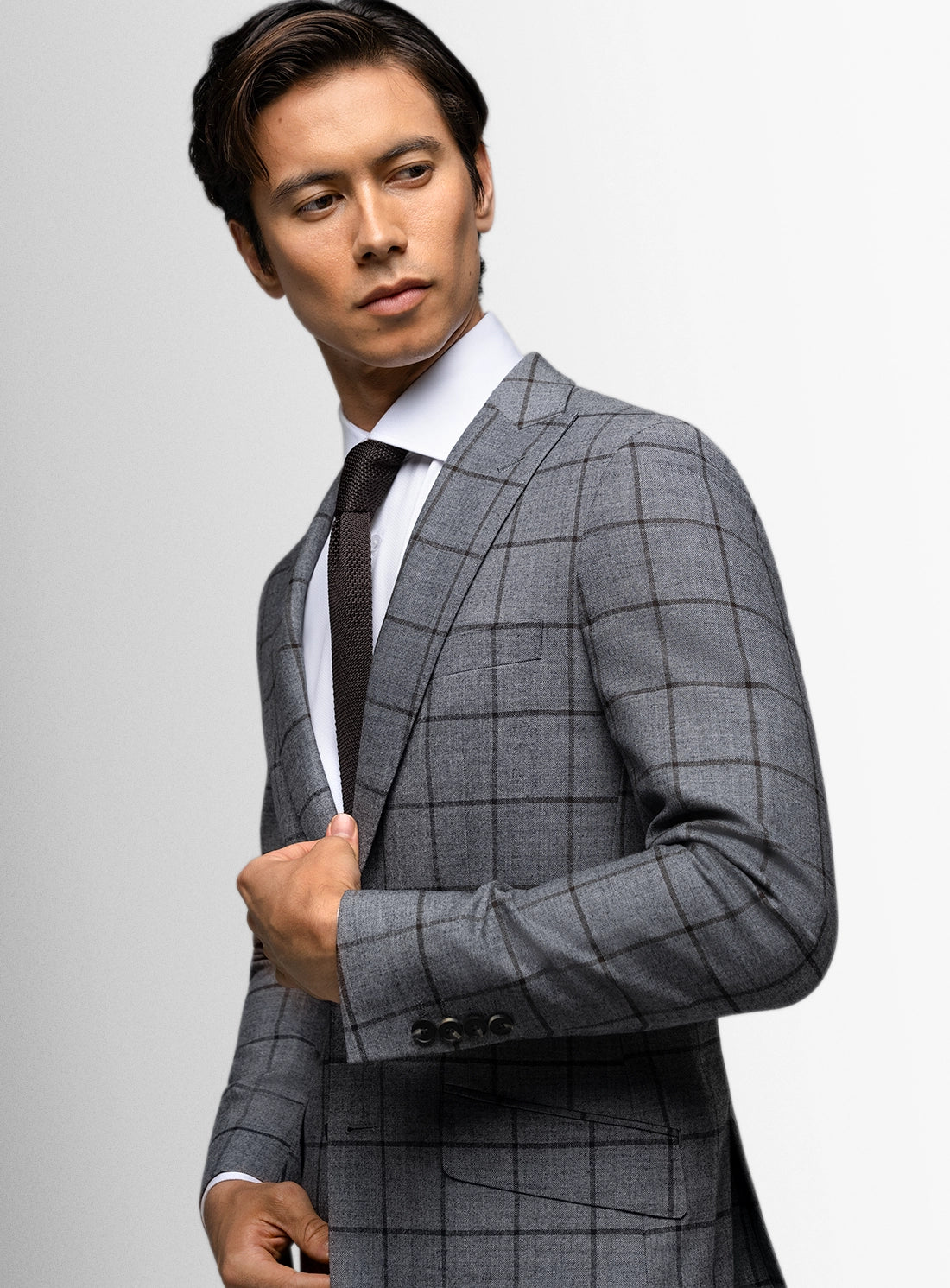 Man wearing a gray checkered suit against a light gray background