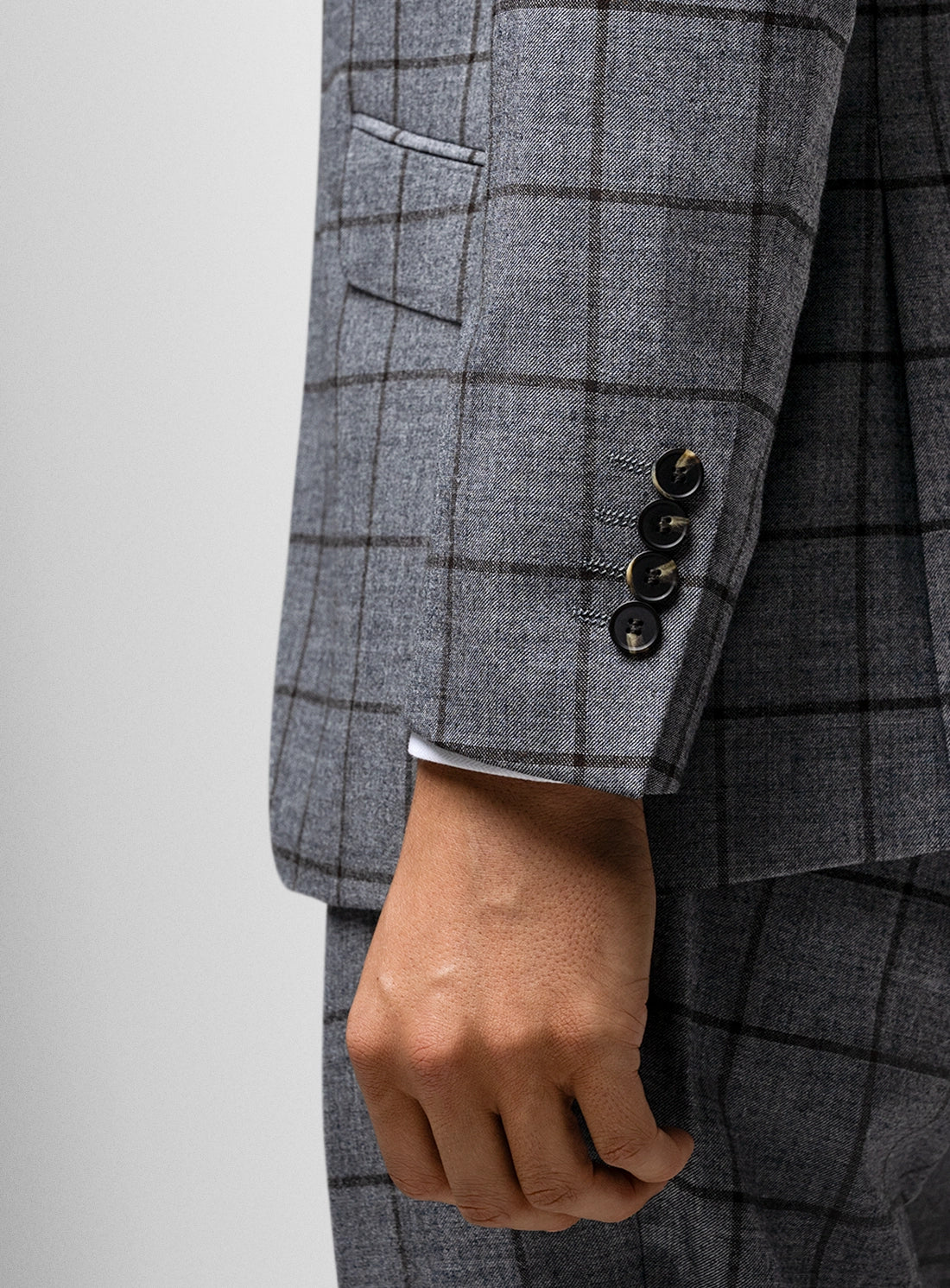 Gray checkered suit jacket with a hand visible on a light gray background