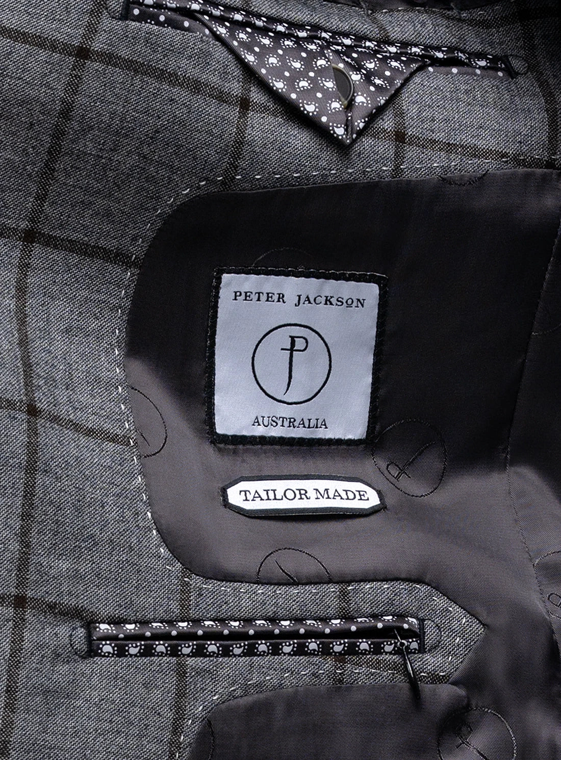 Close-up of a Peter Jackson Australia tailor-made label on a gray plaid fabric.