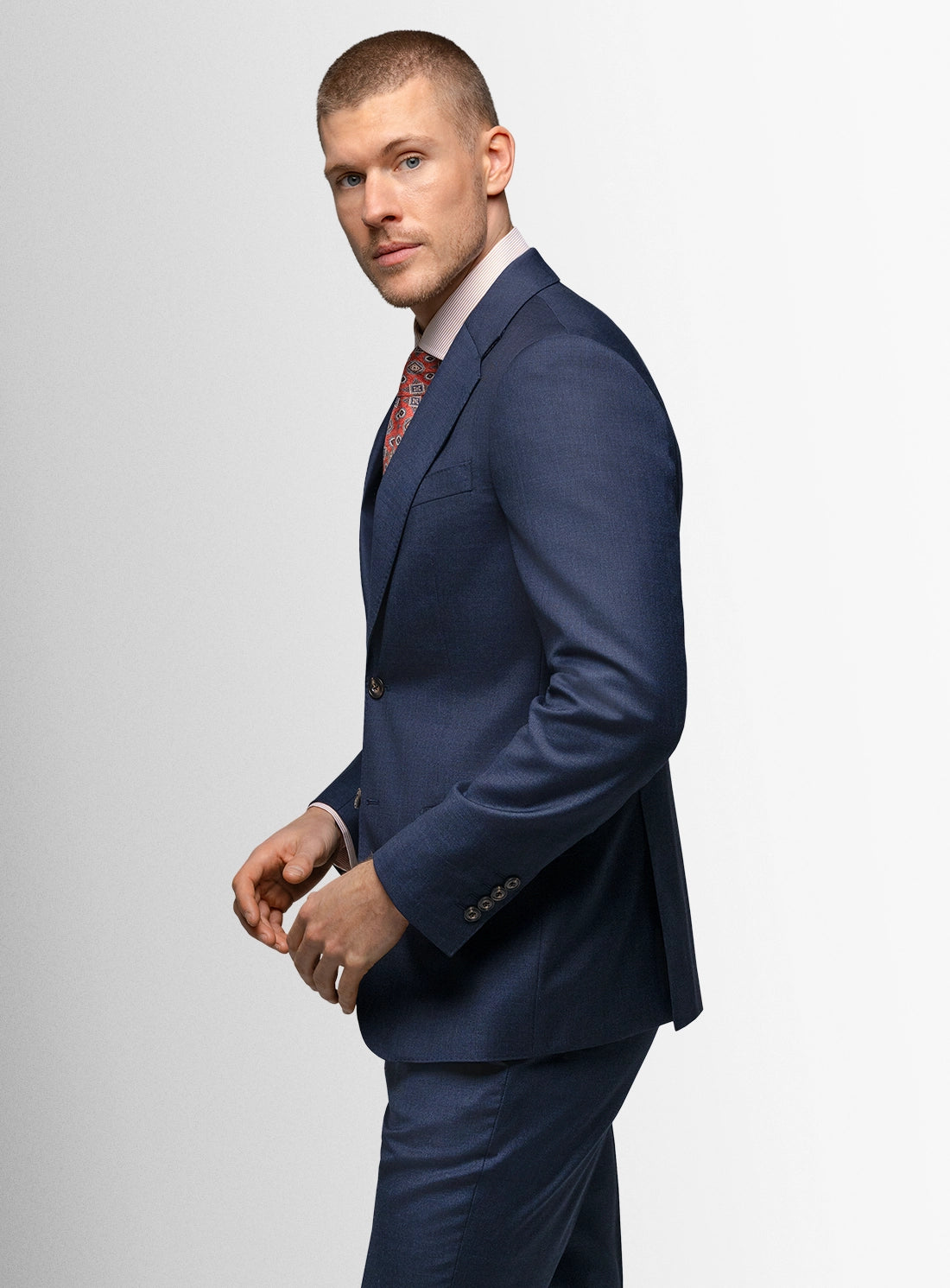 Man wearing a blue suit with a red tie on a light gray background