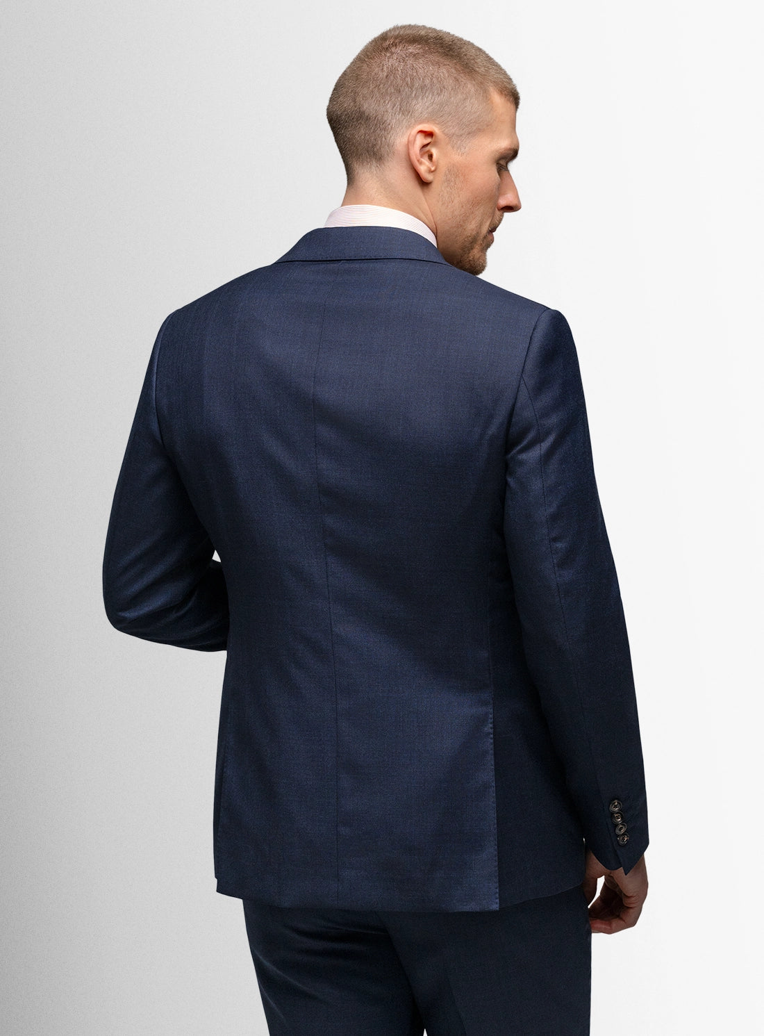 Man wearing a navy blue suit jacket on a light gray background