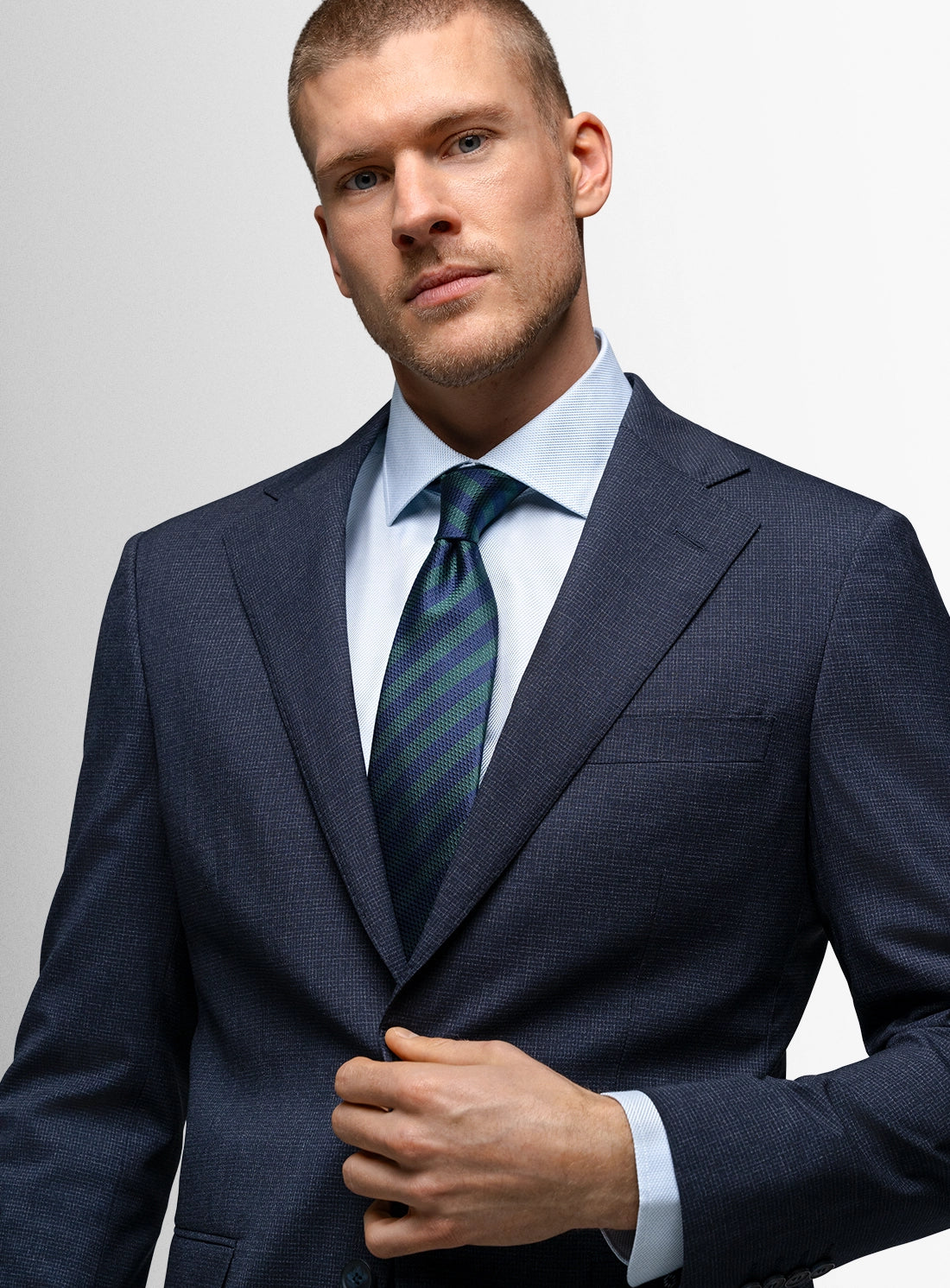 Man wearing a dark suit with a striped tie against a light gray background
