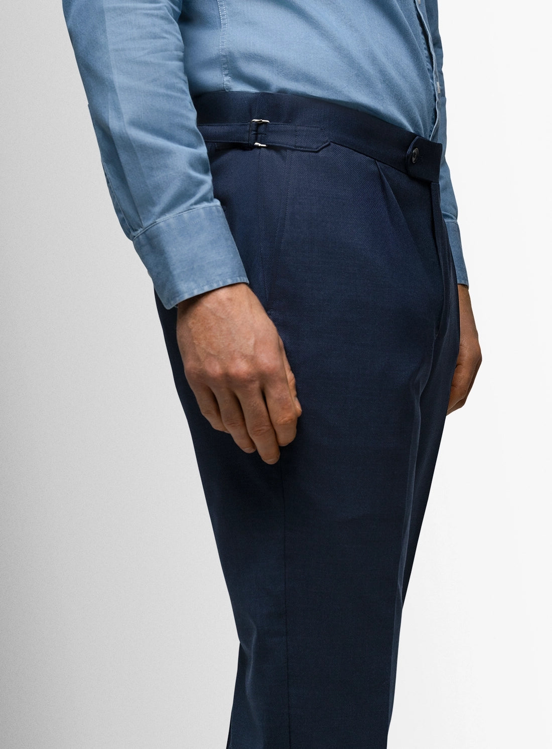 Navy pants worn with a light blue shirt on a plain background