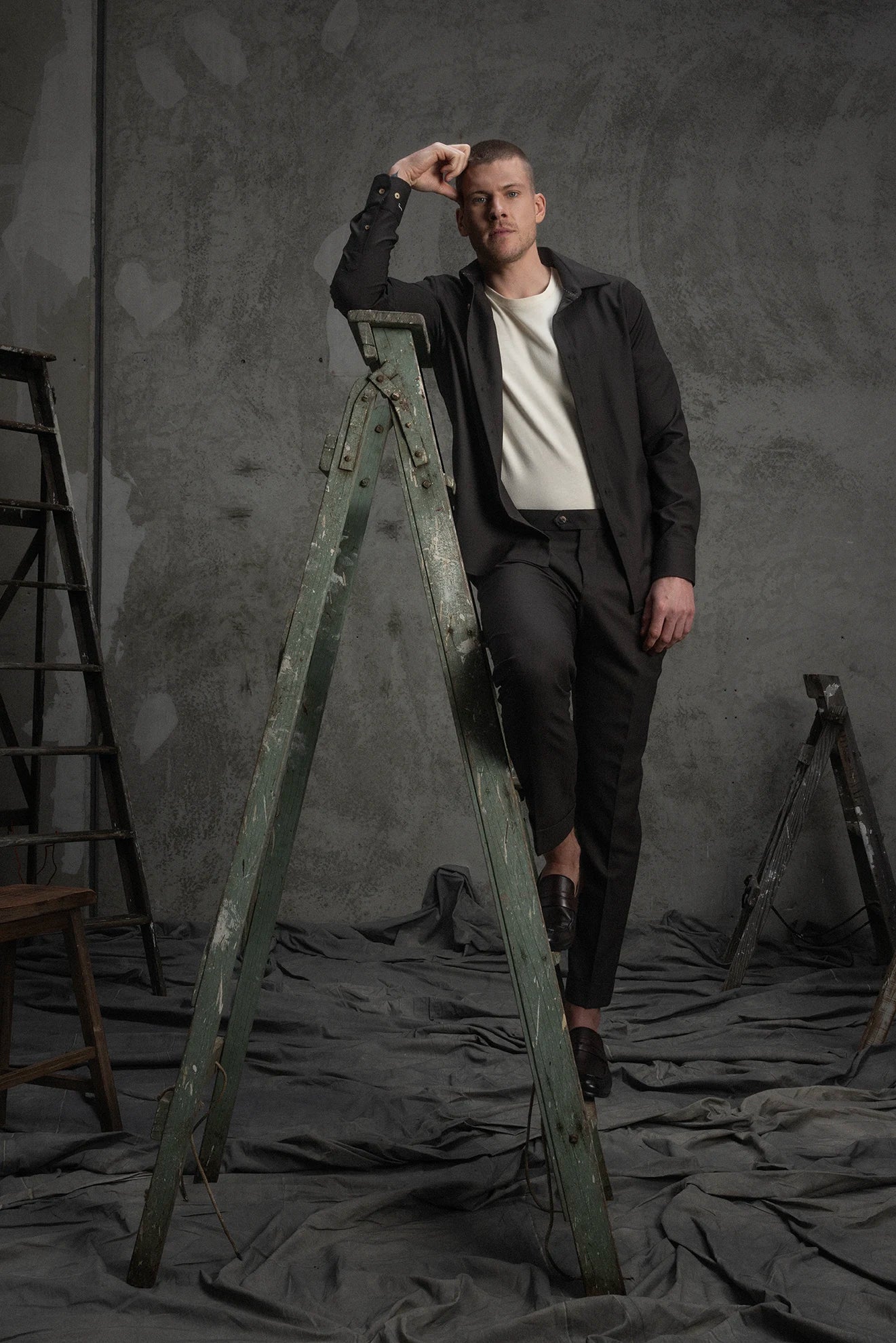 Man standing on a wooden ladder against a textured gray wall