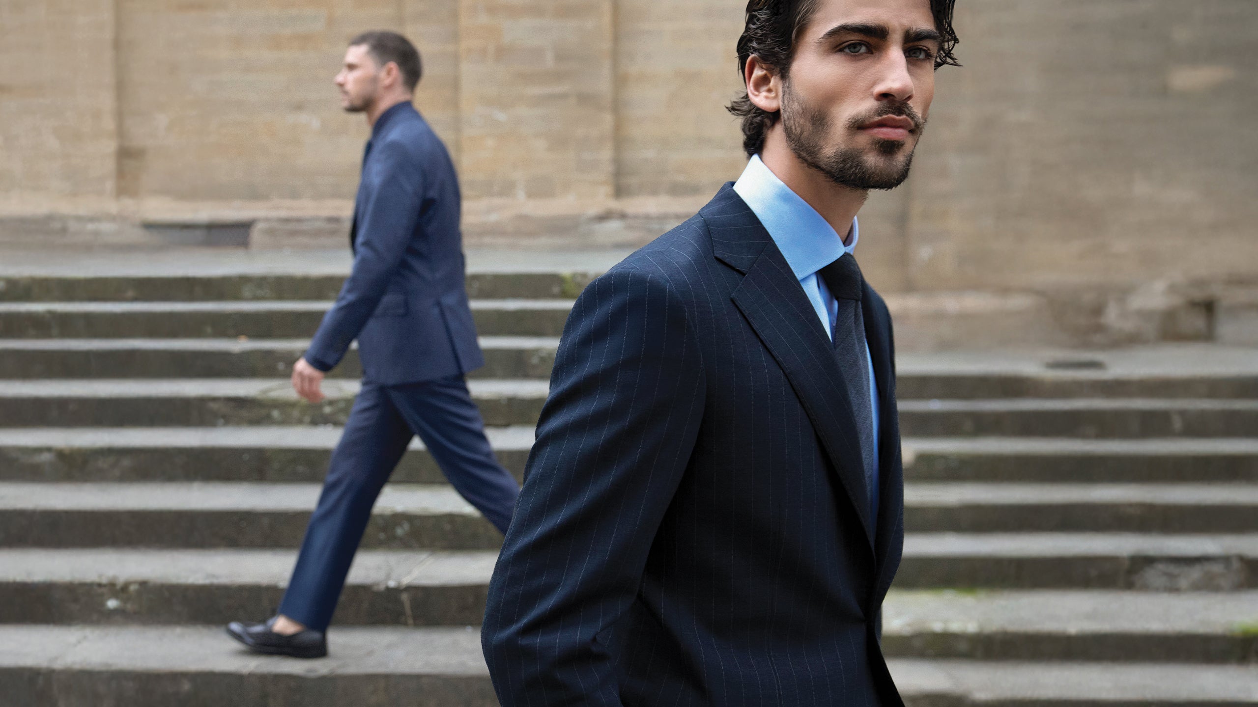 Man in a suit walking up steps with another person in the background