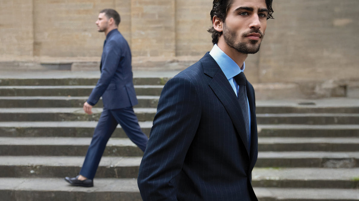 Man in a suit walking up steps with another person in the background