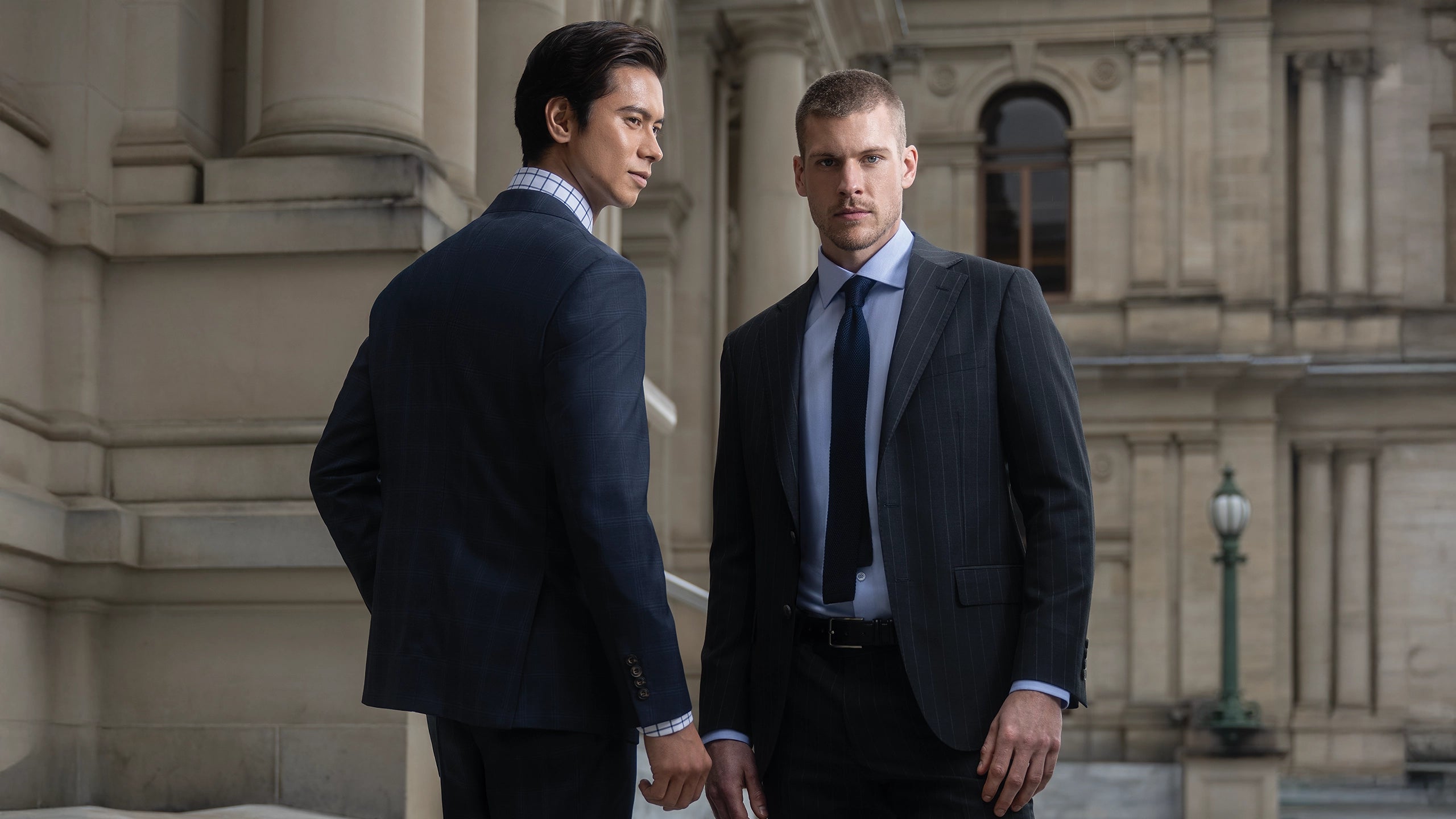 Two men in suits standing in front of a classical building