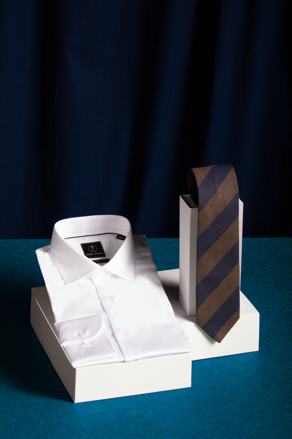White dress shirt and striped tie on a stand against a dark background