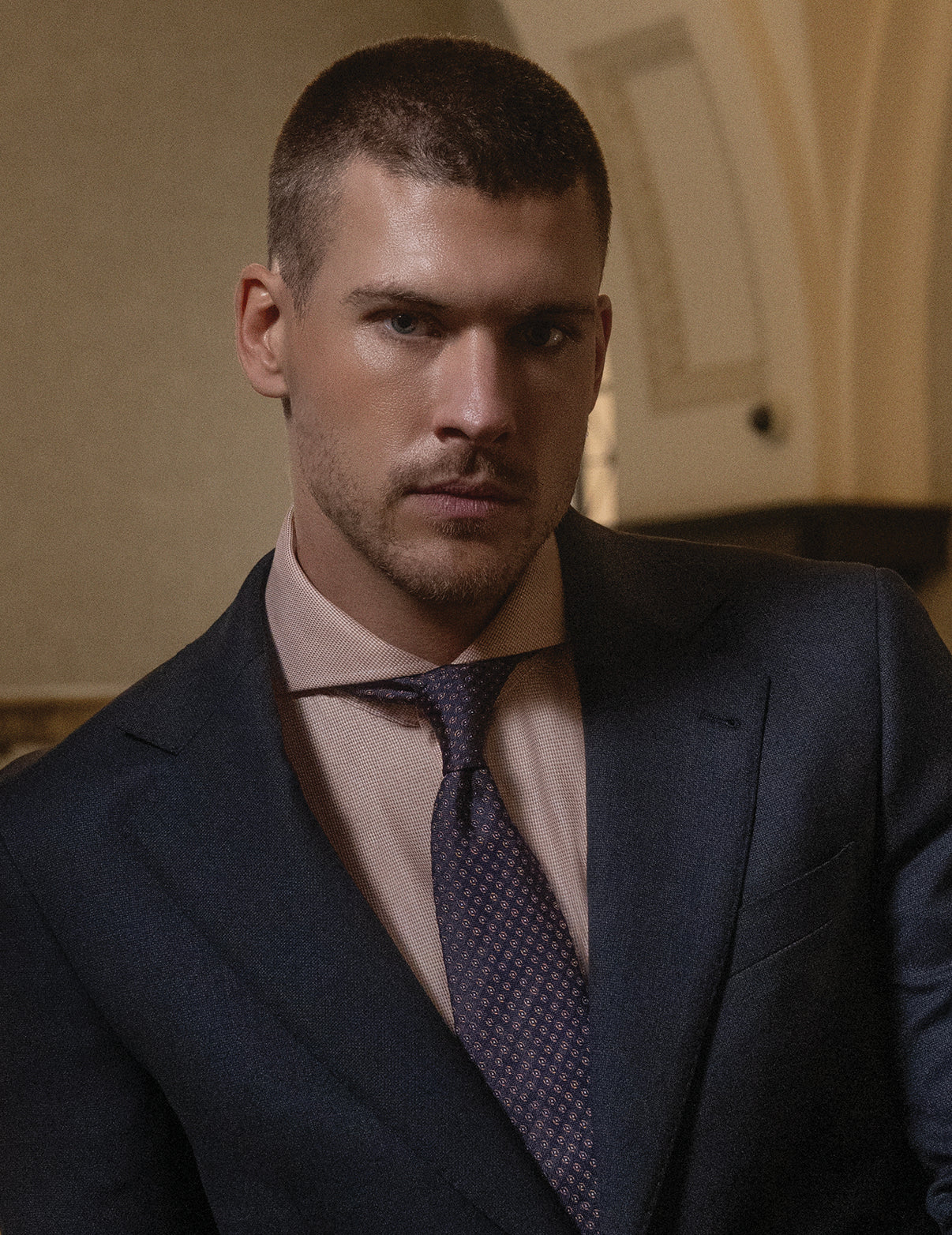 Man wearing a dark suit and purple tie in an indoor setting