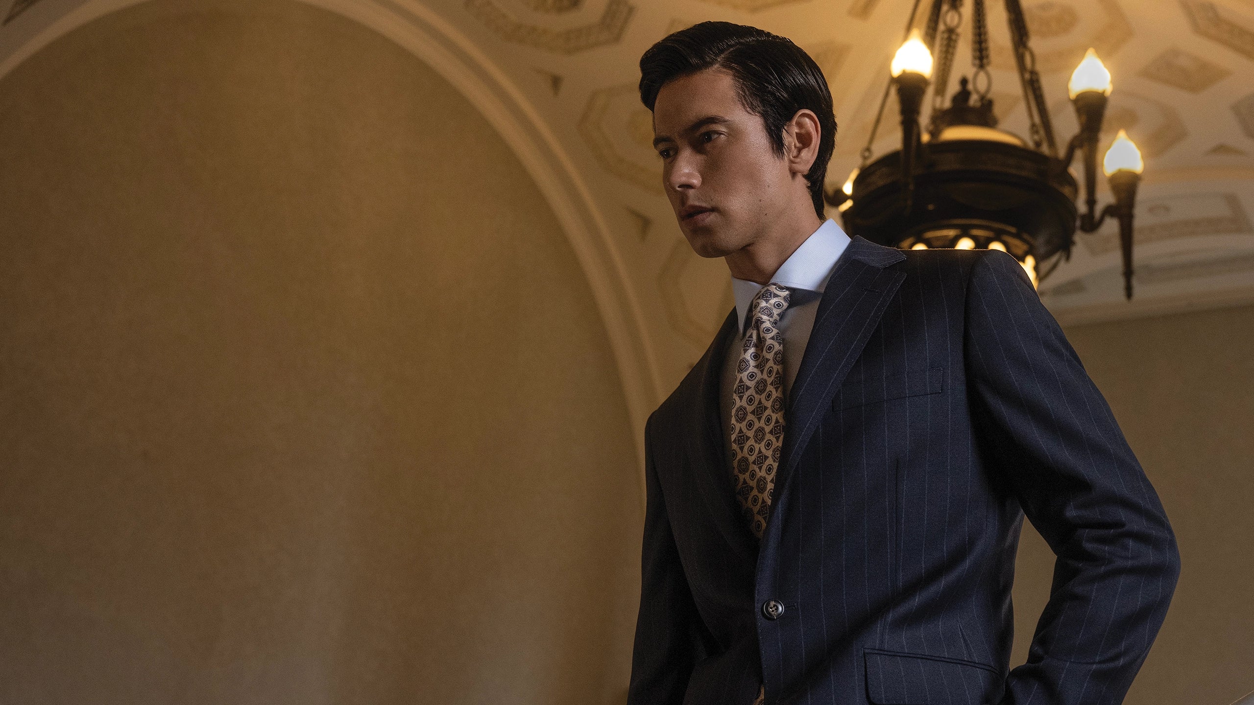 Man in a suit with a chandelier in the background