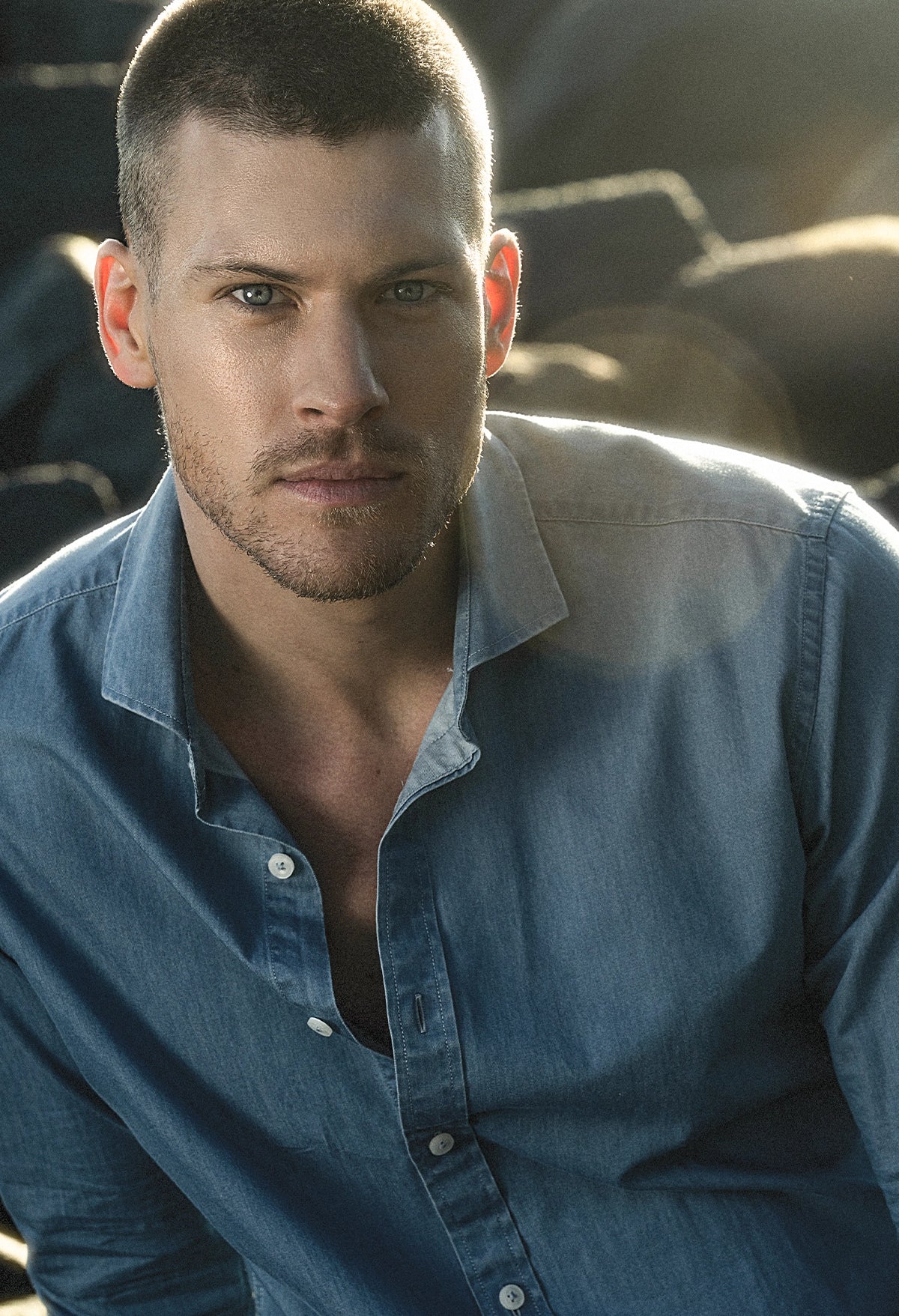 Man wearing a blue denim shirt with a blurred outdoor background