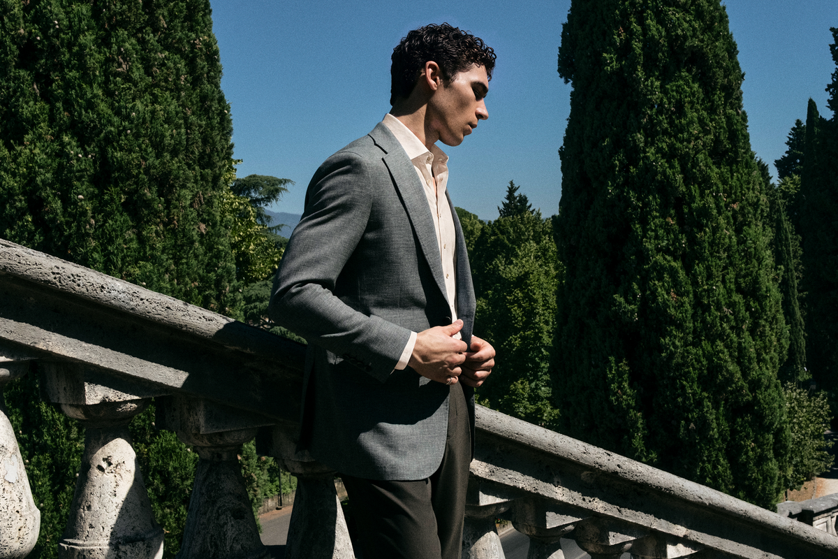 Man in a grey suit standing in a garden courtyard