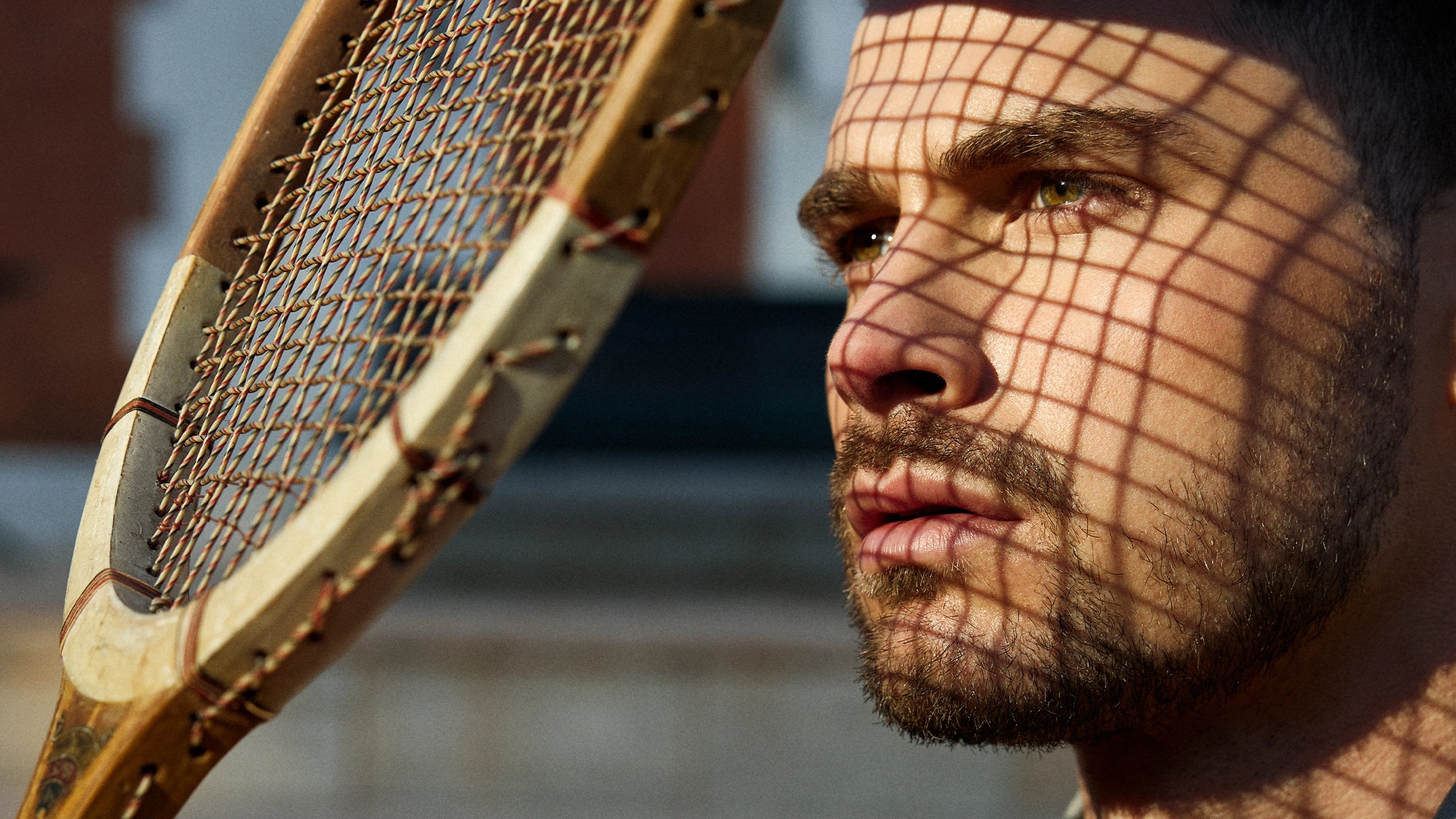 Man holding a vintage tennis racket with a blurred background