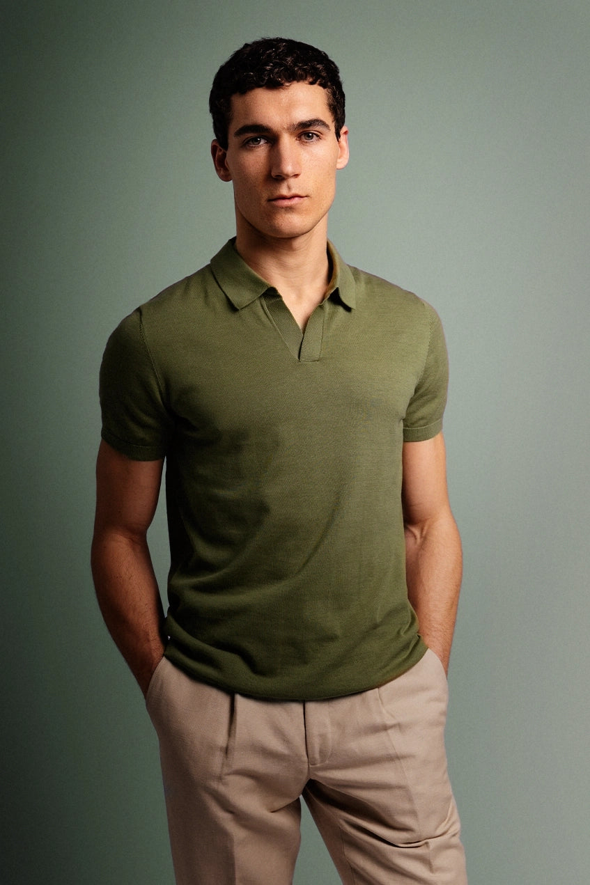 Man wearing a green polo shirt and beige pants against a gray background