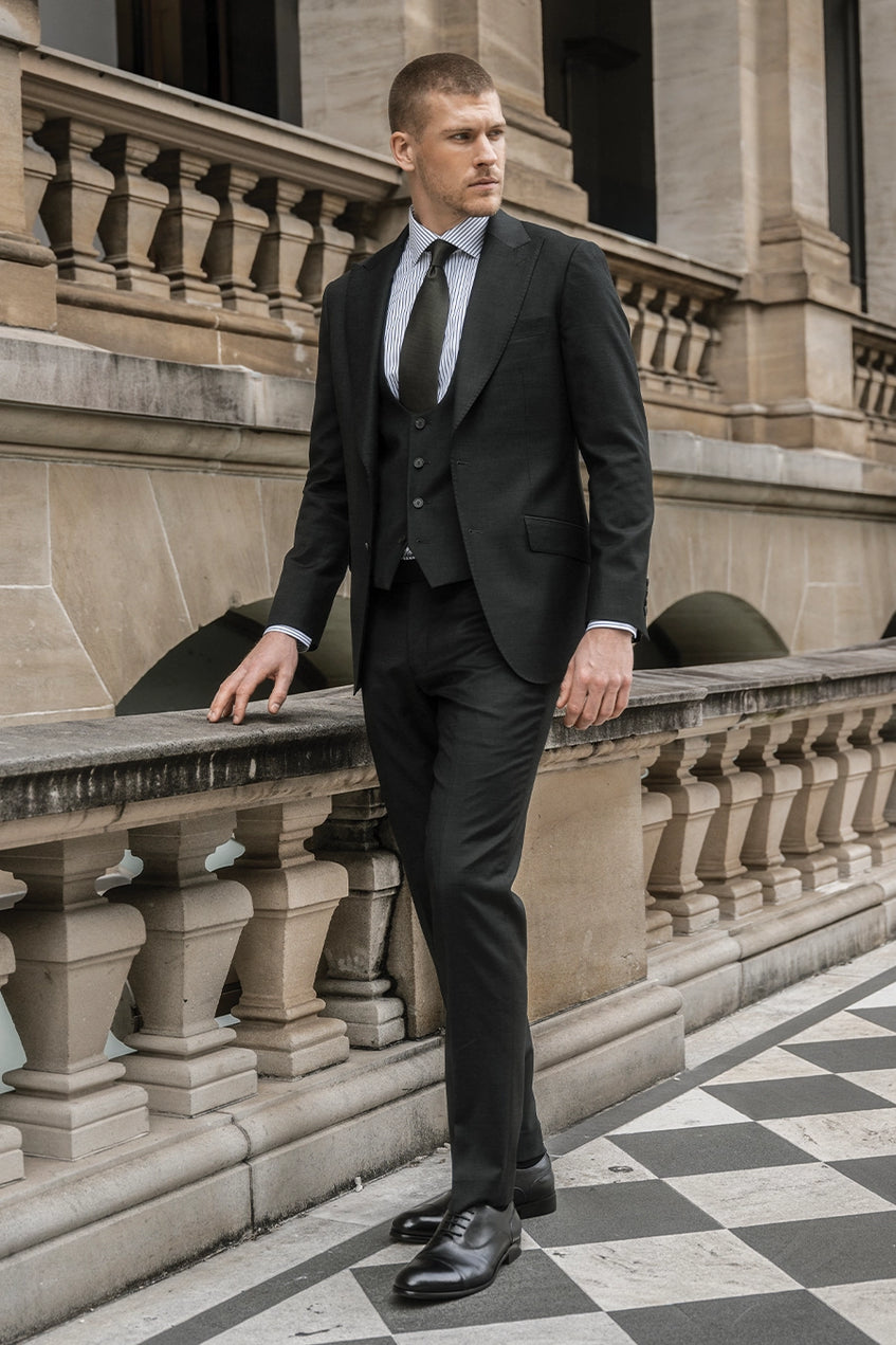 Man wearing forest green suit standing next to a building