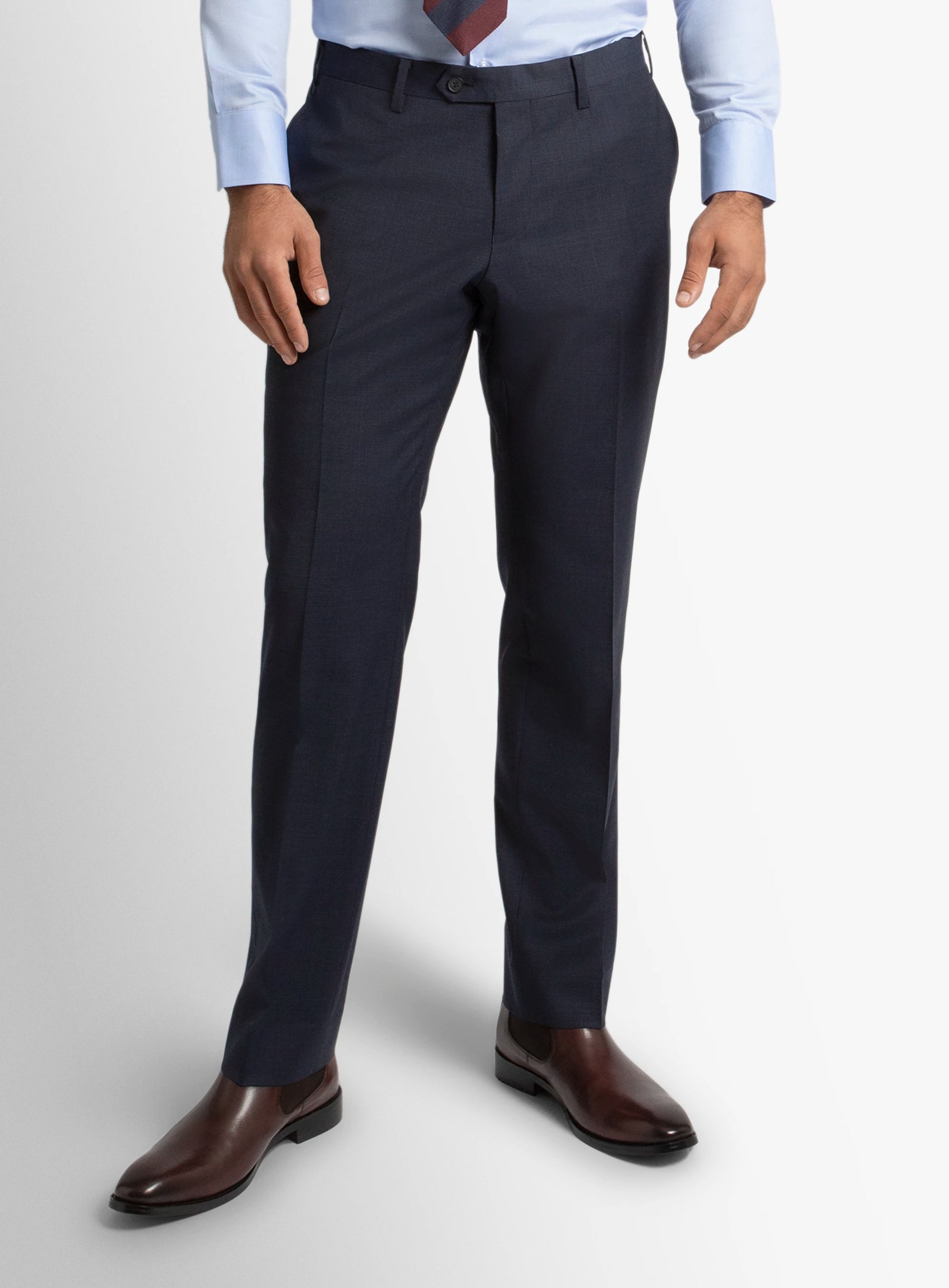 Dark gray dress pants worn with a light blue shirt and brown shoes on a white background