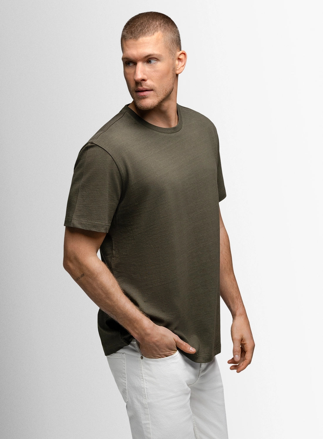 Man wearing a green t-shirt and white pants on a gray background